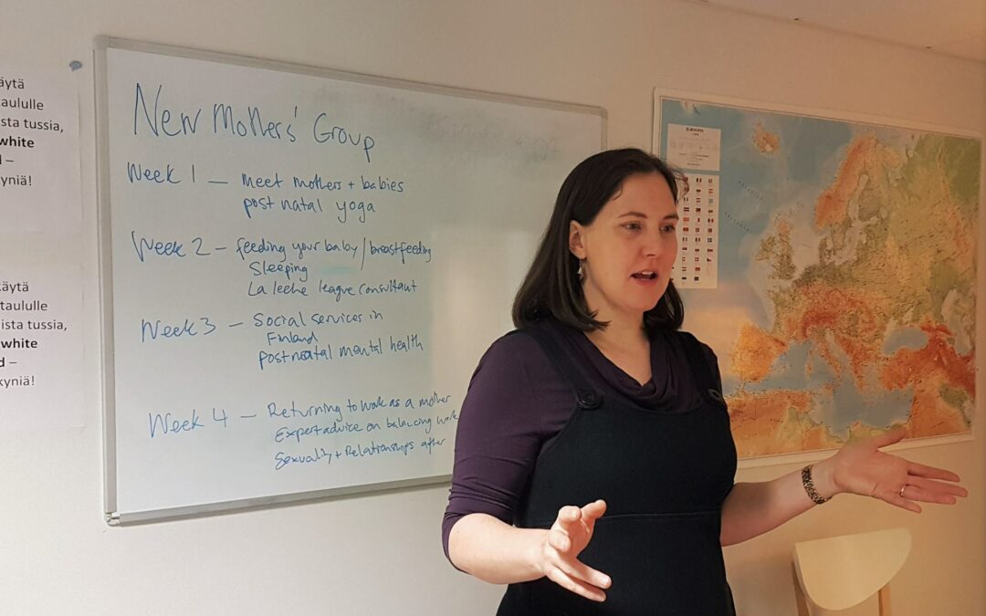 Annabel Battersby speaking in front of whiteboard with "New Mothers' Group" written on it