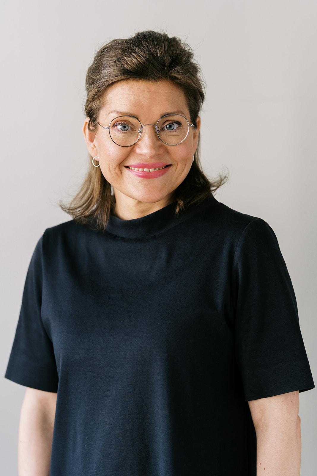 Compass Psychology Portrait of smiling white woman with round glasses, chin-length mid-brown hair, and dark green knitted sweater.