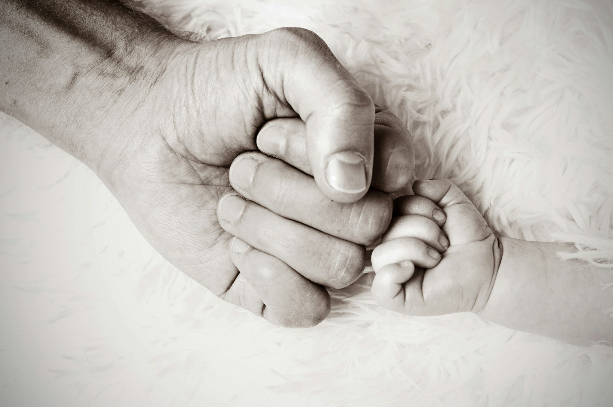 Photo of a man's fist bumping a baby's fist